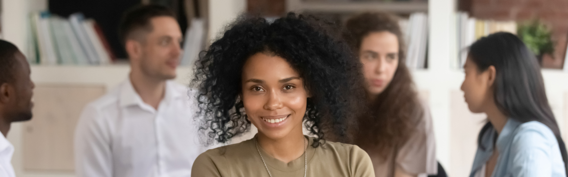 woman smiling while people at the back are having a conversation